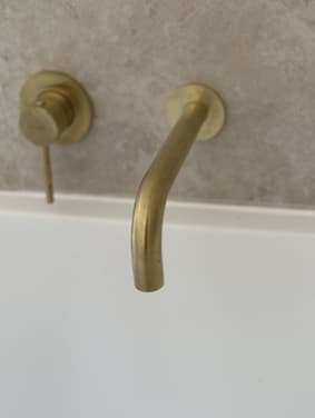 Brass wall-mounted bath spout close-up